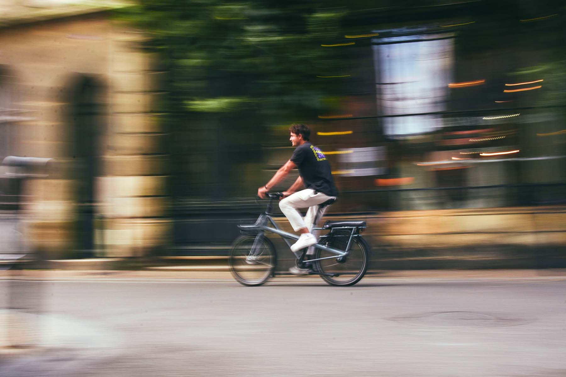 Man riding a bicycle through the city with motion blur in the background