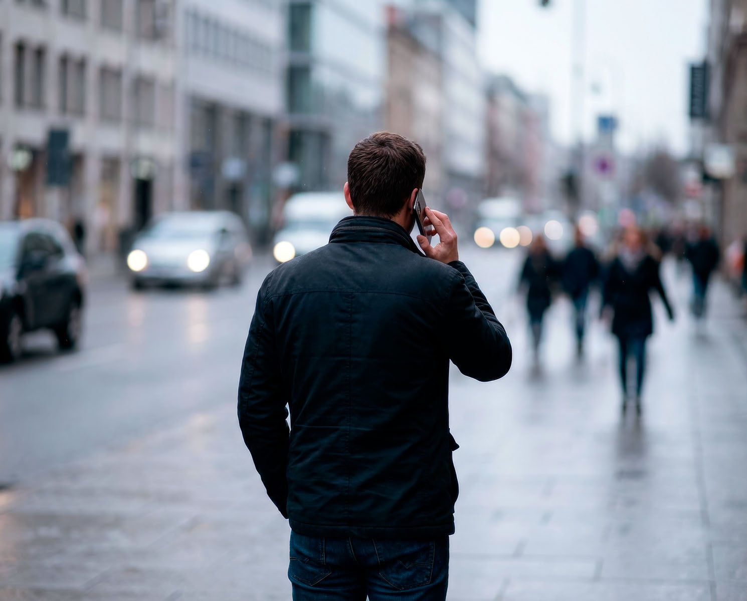 Man walking through a busy city street while talking on the phone